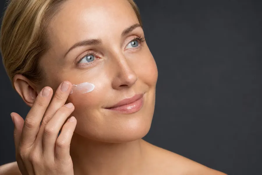 Donna che si applica una crema sul viso (immagine illustrativa)